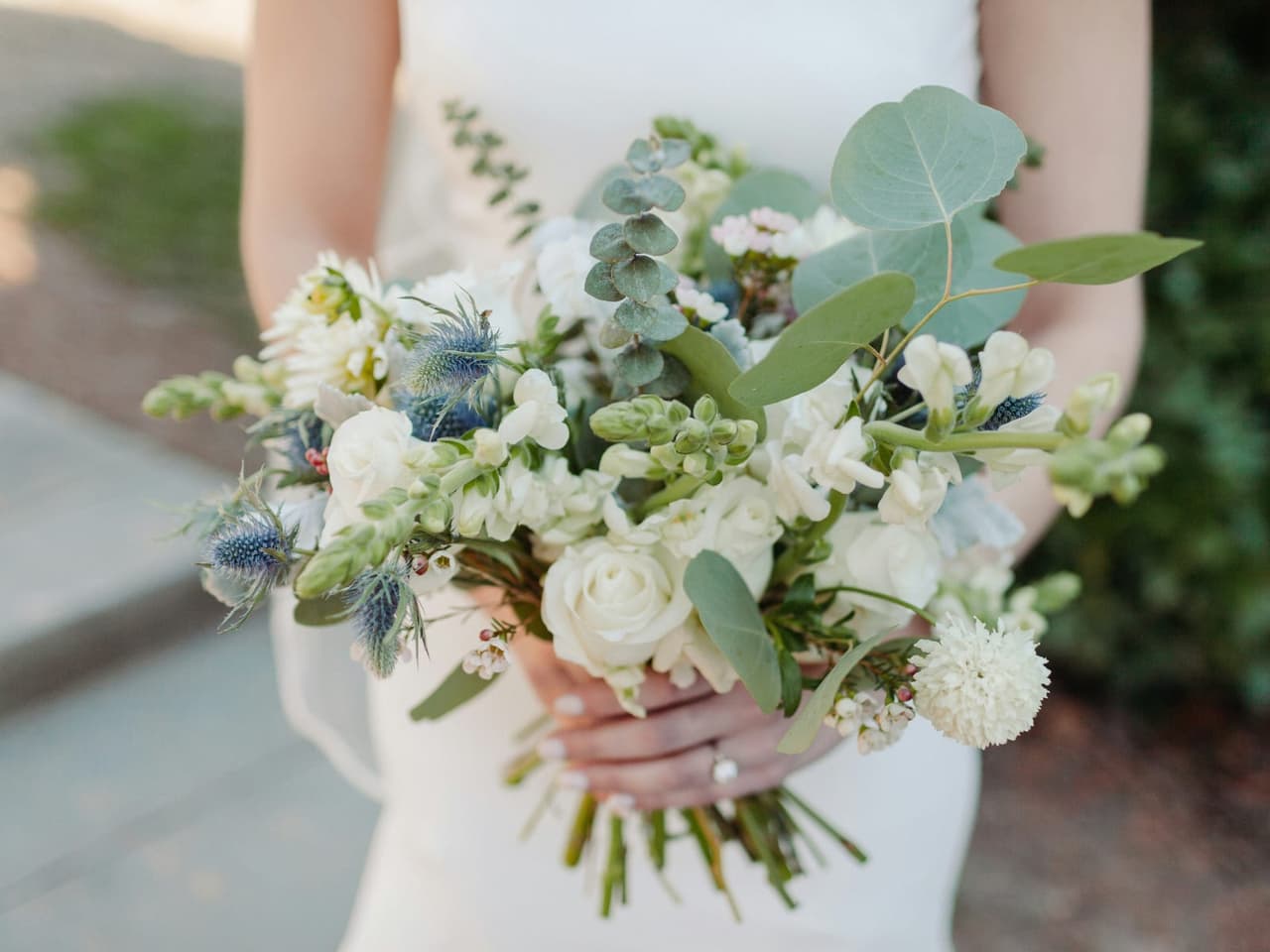 Bouquet de mariée en fleurs blanches et eucalyptus, tenu par la mariée